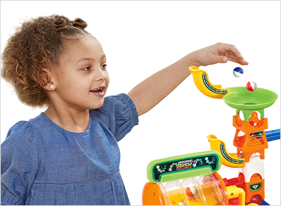 Child dropping several marbles into the top of of the track and watches as they roll down.